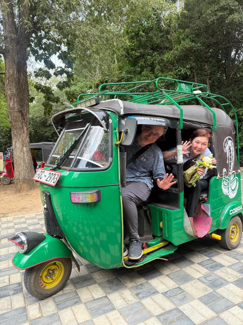 Travellers riding in a green tuk-tuk on a countryside road