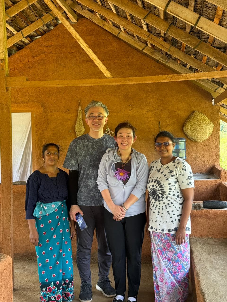 Travellers with their local hosts inside a traditional wattle-and-daub village home