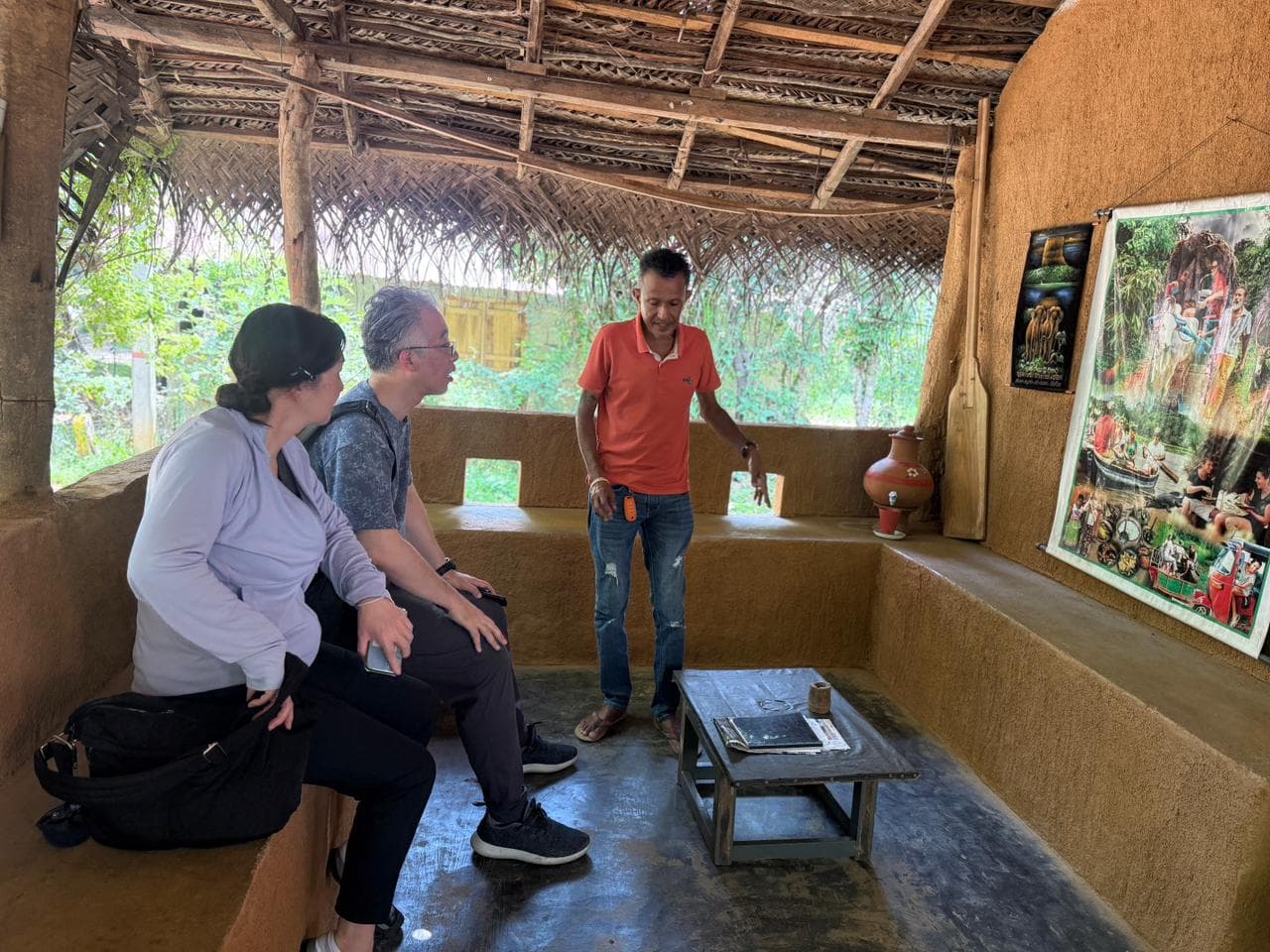 A local guide talking with travellers inside a traditional village hut