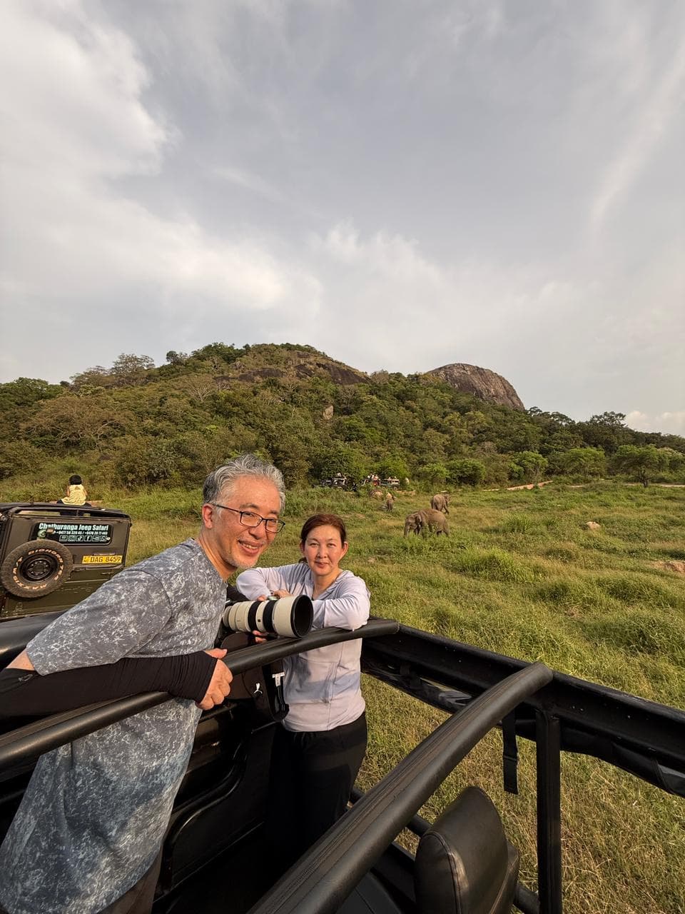 Travellers on a safari jeep with a rock outcrop in the background